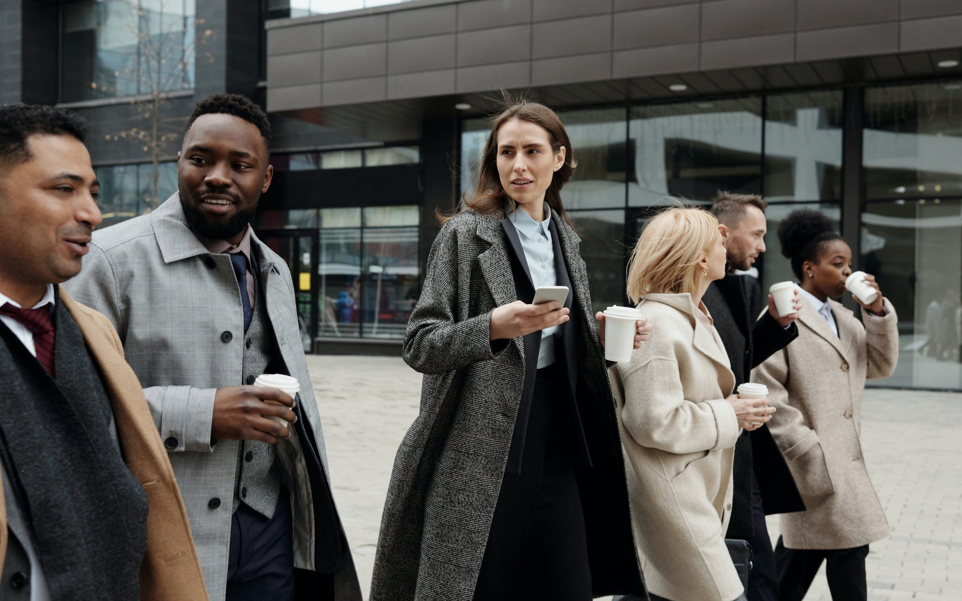 A group of workers walk to an office carrying coffee cups